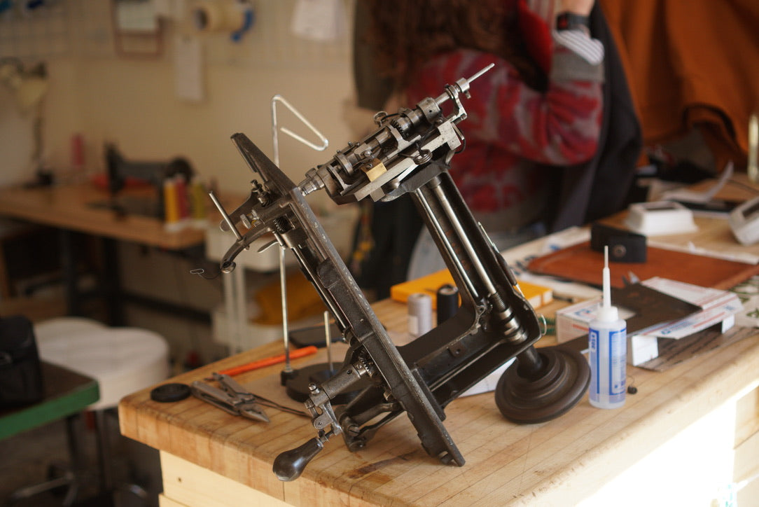 A cornely chainstitch embroidery machine with its cover plate taken off for cleaning and oiling.